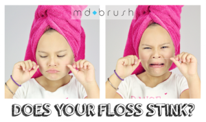 little girl smelling dental floss md brush